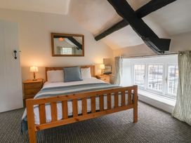 A bedroom with a wooden bed and two bedside tables with lamps at Dragon House in Bilbrook near Minehead