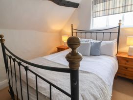A bedroom with a metal bed frame two bedside tables with lamps and a window with striped blinds at Dragon House in Bilbrook near Minehead