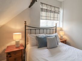 A bedroom with a bed with white bedding and pillows two bedside tables with lamps and a window with a striped blind at Dragon House in Bilbrook near Minehead