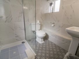 A bathroom with a toilet shower area and a pedestal sink at Dragon House in Bilbrook near Minehead