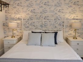 A bedroom with a white metal bed frame two bedside tables with lamps and coastal wallpaper at Dragon House in Bilbrook near Minehead