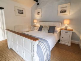 A bedroom with a bed between two nightstands each with a lamp and pictures on the wall at Dragon House in Bilbrook near Minehead