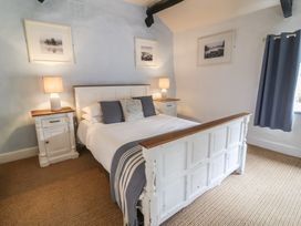 A bedroom with a white wooden bed and bedside tables with lamps at Dragon House in Bilbrook near Minehead