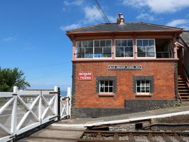 A brick signal box building with windows and signs near a railway crossing gate at Blue Anchor Signal Box in Bilbrook near Minehead