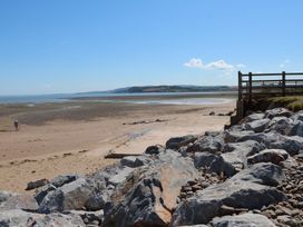 A sandy beach with large rocks and a wooden fence near the shore at Dragon House in Bilbrook near Minehead