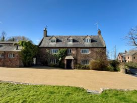 A stone house with ivy on the walls and a gravel driveway in front at Dragon House in Bilbrook near Minehead