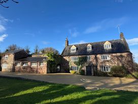 A stone house with multiple windows and ivy on the walls under a blue sky at Dragon House in Bilbrook near Minehead