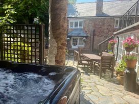 An outdoor area with a hot tub and dining furniture at Dragon House Bilbrook near Minehead