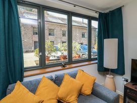 A living room with a sofa and view through the window at 8 Pottery Cottages