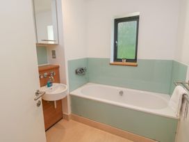 A bathroom with a bathtub, sink and mirror at 8 Pottery Cottages