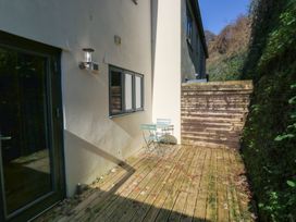 A garden area with a wooden deck and chairs at 8 Pottery Cottages