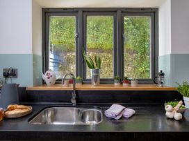 A kitchen with a sink, plants and cooking utensils at Mariners Retreat, 8 Pottery Cottages Dartmouth