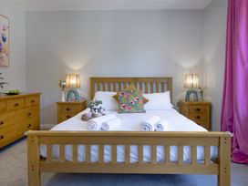 A bedroom with a wooden bed and bedside lamps at Mariners Retreat, 8 Pottery Cottages in Dartmouth