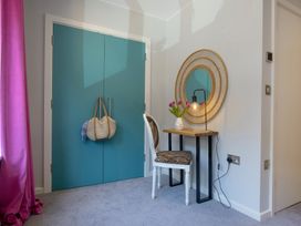 A corner with a table, a chair, and a mirror in a bedroom at Mariners Retreat, 8 Pottery Cottages, Dartmouth