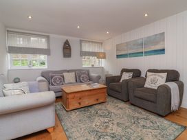 A living room with sofas armchairs a wooden coffee table and paintings at Gatekeeper's Cottage Bilbrook near Minehead