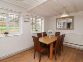 A dining room with a wooden table and six brown chairs at Gatekeeper's Cottage Bilbrook near Minehead