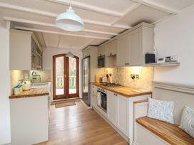 A kitchen with wooden countertops a gas stove a built in oven a refrigerator a sink and a wooden bench with cushions at Gatekeeper's Cottage in Bilbrook near Minehead