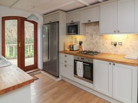 A kitchen with wooden countertops white cabinets a stainless steel refrigerator and an oven with a stovetop at Gatekeeper's Cottage in Bilbrook near Minehead