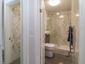 A bathroom with a toilet, sink, shower area, towel rack, and marble-patterned walls at Gatekeeper's Cottage Bilbrook near Minehead