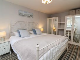 A bedroom with a white metal bed frame striped carpet and a wardrobe with mirrored doors at Gatekeeper's Cottage Bilbrook near Minehead
