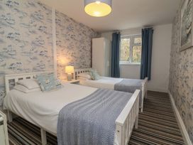 A bedroom with two single beds a nightstand with a lamp a wardrobe and striped carpet at Gatekeepers Cottage in Bilbrook near Minehead