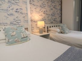 A bedroom with two single beds a nightstand with a lamp and nautical-themed wallpaper and cushions at Gatekeeper's Cottage in Bilbrook near Minehead