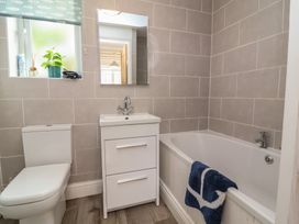 A bathroom with a toilet sink with cabinet bathtub and window at Gatekeeper's Cottage Bilbrook near Minehead