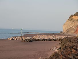 A beach with rocks and a cliff on the right side at Gatekeeper's Cottage in Bilbrook near Minehead