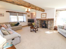 A living room with beige sofas a stone fireplace a wooden coffee table and a TV at High Wood Foot in Bampton Cumbria