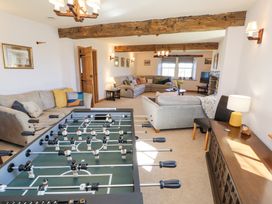 A living room with sofas a foosball table wooden beams and a lamp on a sideboard at High Wood Foot in Bampton Cumbria