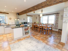 A kitchen and dining area with wooden beams a dining table with chairs and kitchen island at High Wood Foot in Bampton Cumbria
