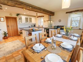 A kitchen and dining area with a wooden table set with dishes and two bottles of wine and a kitchen island at High Wood Foot in Bampton Cumbria