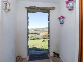 A stone doorway opening to a garden with flowers a welcome mat and decorative wall pots with flowers at High Wood Foot in Bampton Cumbria