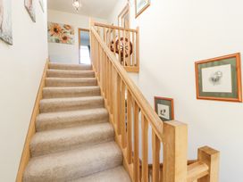 A carpeted staircase with wooden railing and framed pictures on the wall at High Wood Foot in Bampton Cumbria