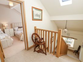 Upstairs hallway with wooden railing and spinning wheel next to bedroom with twin beds at High Wood Foot in Bampton Cumbria