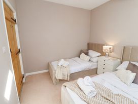 A bedroom with two single beds a white nightstand with a lamp and a wooden door at High Wood Foot in Bampton Cumbria
