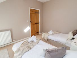 A bedroom with two single beds and a wooden door at High Wood Foot in Bampton Cumbria