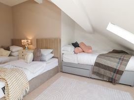 A bedroom with two single beds a bedside table with a lamp and pillows at High Wood Foot in Bampton Cumbria