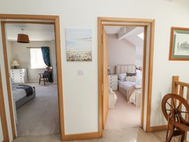 Two bedrooms visible through open doors with beds dressers and chairs in a hallway at High Wood Foot in Bampton Cumbria