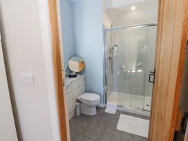 A bathroom with a toilet a shower cubicle and a counter with a round mirror at High Wood Foot in Bampton Cumbria