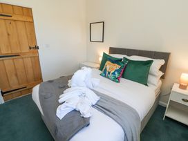 A bedroom with a bed with green and cheetah print pillows bedside tables with lamps and a wooden door at High Wood Foot in Bampton Cumbria