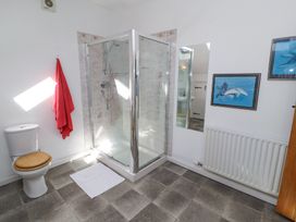 A bathroom with a shower cubicle a toilet with a wooden seat a red towel hanging and dolphin pictures on the wall at High Wood Foot in Bampton Cumbria