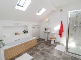 A bathroom with a bathtub wooden toilet seat pedestal sink shower and skylight windows at High Wood Foot in Bampton Cumbria