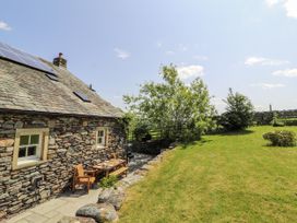 A stone house with a table and chairs in a garden at High Wood Foot, Bampton, Cumbria