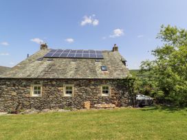 A stone house with solar panels and a garden at High Wood Foot in Bampton, Cumbria