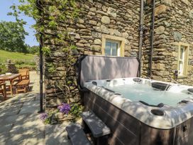 An outdoor area with a hot tub and wooden furniture at High Wood Foot Bampton, Cumbria
