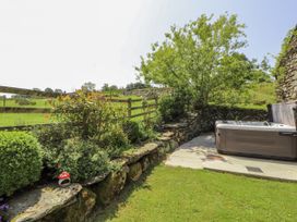 An outdoor area with a hot tub and stone wall at High Wood Foot in Bampton, Cumbria
