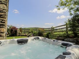 A hot tub with water in a garden area at High Wood Foot, Bampton, Cumbria