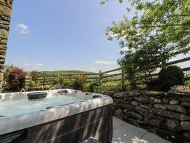 A hot tub next to a stone wall with plants at High Wood Foot in Bampton, Cumbria