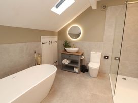 A bathroom with a bathtub, sink, and shower at High Wood Foot, Bampton, Cumbria